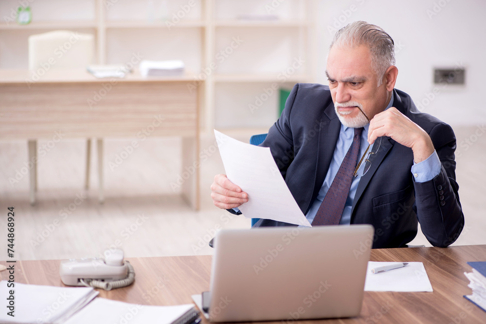 Old male employee working in the office Old male employee working in the office