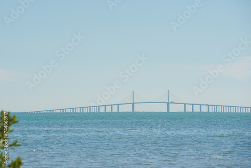 Wide View from beach at Maximo Park in St Petersburg Florida towards  the Sunshine Skyway bridge in Tampa Bay. Small waves on blue water late afternoon sun.    © Del Harper