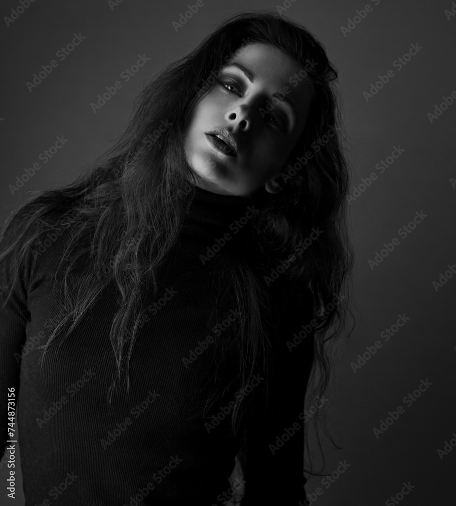 Beautiful makeup sensual woman with brown long hair and black dress looking on dark shadow background. Closeup Beautiful makeup sensual woman with brown long hair and black dress looking on dark shadow background. Closeup