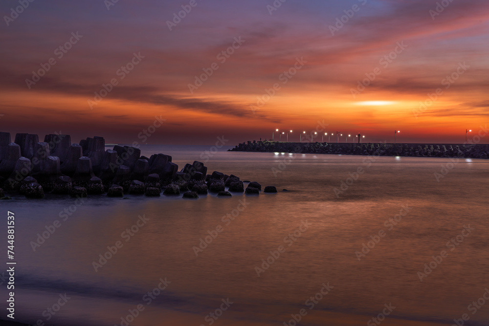 Stunning sunset blues hour view. Magnificent, beautiful breakwater, red cloudy sky form a scenic scene.High quality photo. Linyuan, Kaohsiung, Taiwan.For branding, screensavers, websites, postcard.
