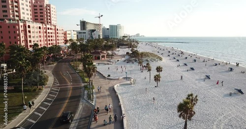 4K high resolution aerial drone video footage of a sandy beach on a sunny day with with some clouds and people, cars, buildings and palm trees in view and a beautiful pier and horizon.