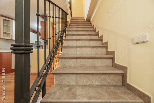 Interior stairs of a duplex residential home with steps with gray tiles and metal railing