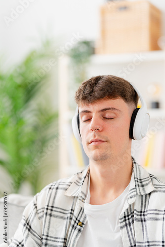 Young man listening relaxing music on headphones with closed eyes