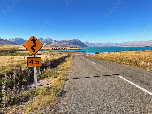 Explore the scenic highway around Mount Cook, winding past Lake Pukaki amidst New Zealand's majestic mountain landscape.