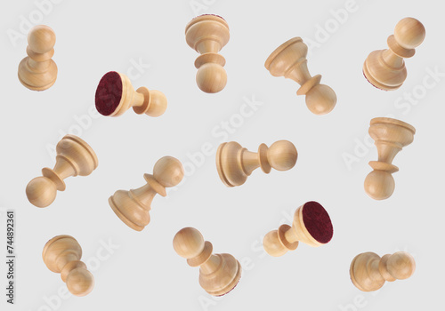 Wooden chess pawns falling on light grey background