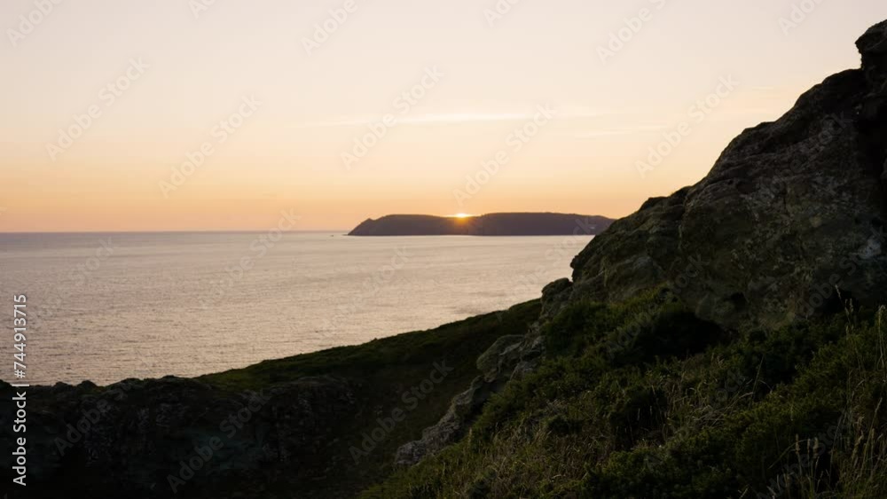 The sun sets behind coastal hills looking over beautiful ocean views The sun sets behind coastal hills looking over beautiful ocean views