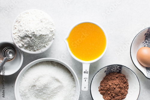 mise en place of ingredients for making brownies, top view of sugar, eggs, butter, flour cocoa powder on a marble table, process of making brownies