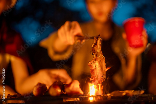 Cheers! Group of asian people friend party camping in nature making barbecue grilled. Hangout party outdoor in campsite nature forest background on holiday weekend vacation in the evening.