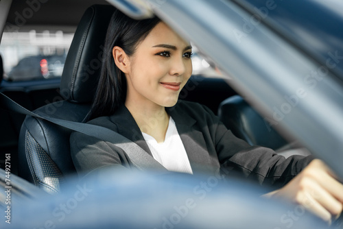 Young beautiful asian business women getting new car. She very happy and excited. Smiling female driving vehicle on the road on a bright day with sun light. Business woman buying driving new car