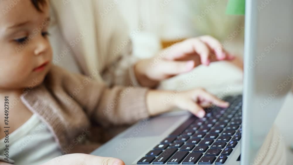 Pretty young single mom working at home on a laptop computer while holding her baby girl Pretty young single mom working at home on a laptop computer while holding her baby girl