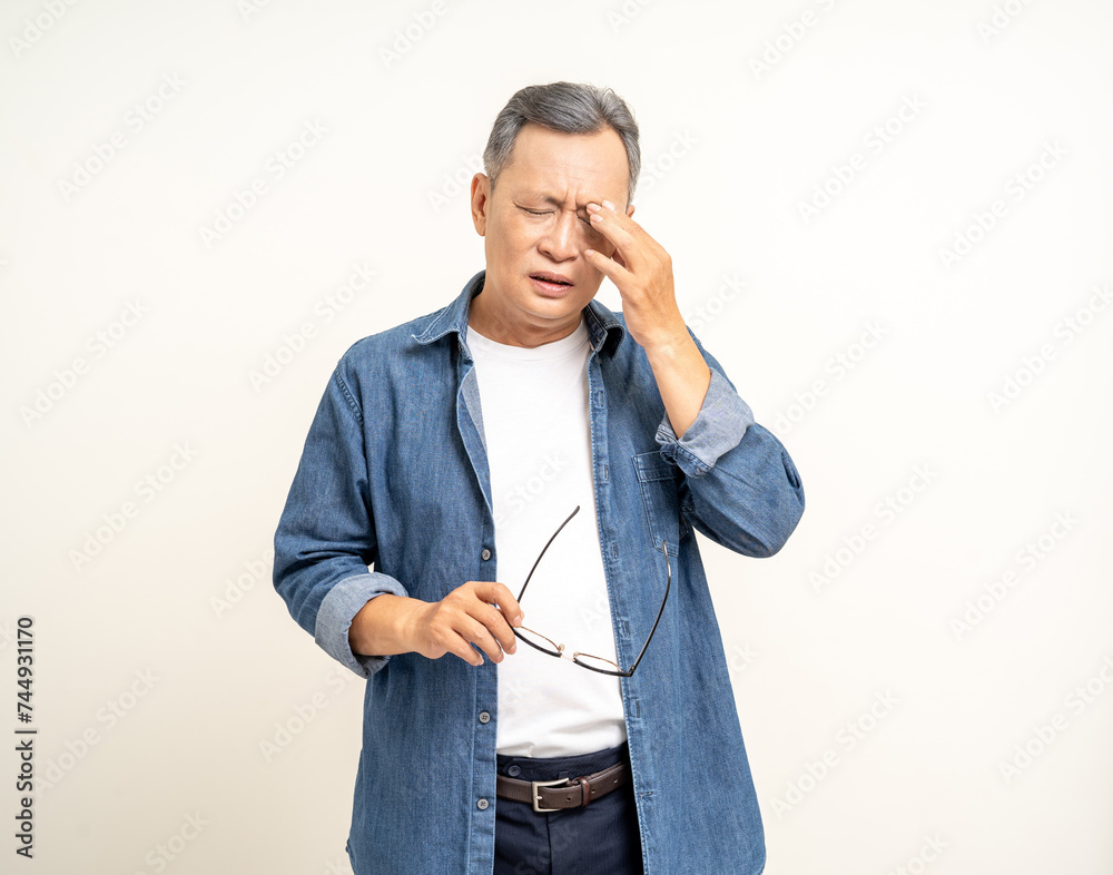 Handsome asian mature old man standing headache hands rubbing eye on isolated white background. Portrait of serious depressed senior asian man eye pain. Mature People and lifestyle Handsome asian mature old man standing headache hands rubbing eye on isolated white background. Portrait of serious depressed senior asian man eye pain. Mature People and lifestyle
