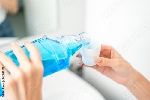 Young asian woman with mouthwash for the health of teeth in restroom. Take care and good dental health fresh breath with mouthwash. photo