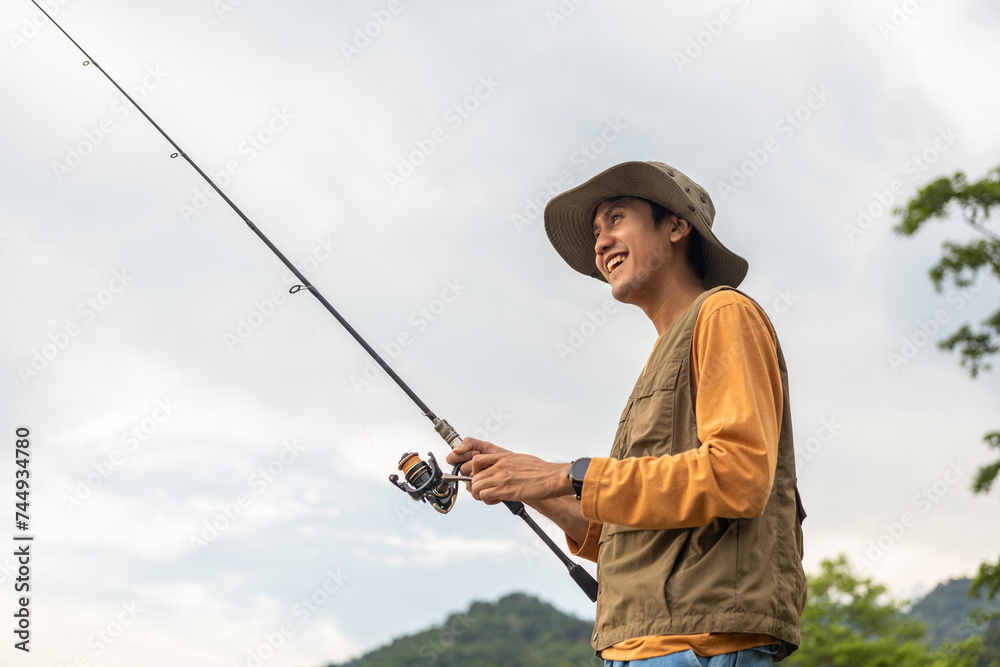 Enjoy moment of Handsome man fishing as a leisure activity during his vacation at the lake on sunset. Silhouette at sunset moment of man fishing rotation with reel. Enjoy moment of Handsome man fishing as a leisure activity during his vacation at the lake on sunset. Silhouette at sunset moment of man fishing rotation with reel.