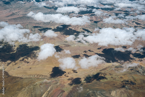 Rainbow colored mountain aerial view with patches of cloud shadow on the ground