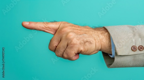 A man's hand pointing left with a thumbs-up gesture on a teal background. photo