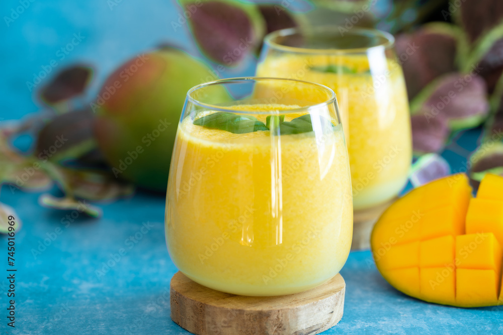 Fresh mango lassi in glasses on blue background with copy space. Fresh mango lassi in glasses on blue background with copy space.