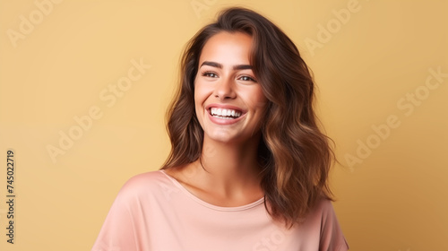 Close up of young woman with white skin, brown hair, wavy hair and a clear pink t shirt, isolated in a light yellow studio. Portrait person.