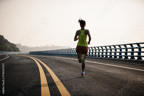 Fitness woman runner running on seaside bridge