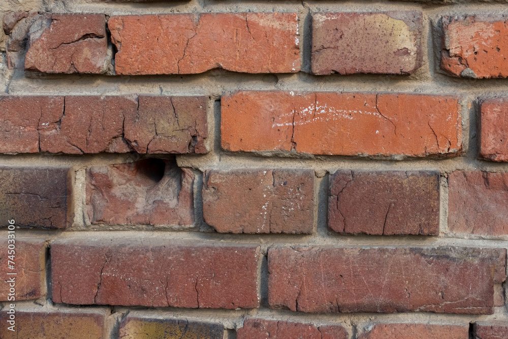 Close-up view of old molded red brick wall covered with craters from military shells, bullets, cracks and scratches. Copy space for your text and decorations. Soft focus. Aftermath of the war theme. Close-up view of old molded red brick wall covered with craters from military shells, bullets, cracks and scratches. Copy space for your text and decorations. Soft focus. Aftermath of the war theme.