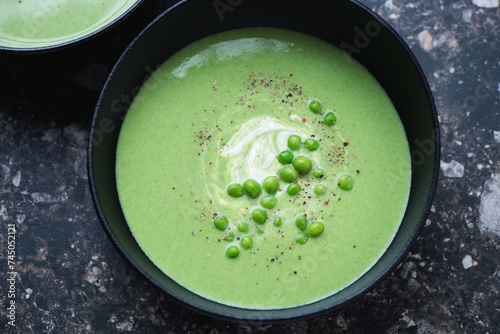 Black bowl with cream-soup made of green peas, horizontal shot, high angle view, middle close-up