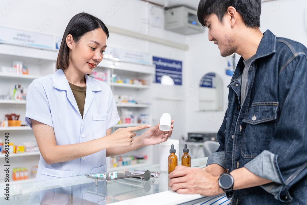 Beautiful asian female pharmacist analyzing about customer symptoms for discussion of the medicine property effect and customer buying pill under prescription order. Beautiful asian female pharmacist analyzing about customer symptoms for discussion of the medicine property effect and customer buying pill under prescription order.