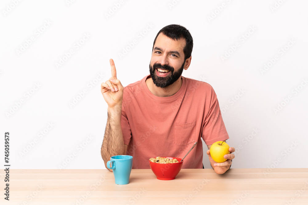 Caucasian man having breakfast in a table showing and lifting a finger in sign of the best. Caucasian man having breakfast in a table showing and lifting a finger in sign of the best.