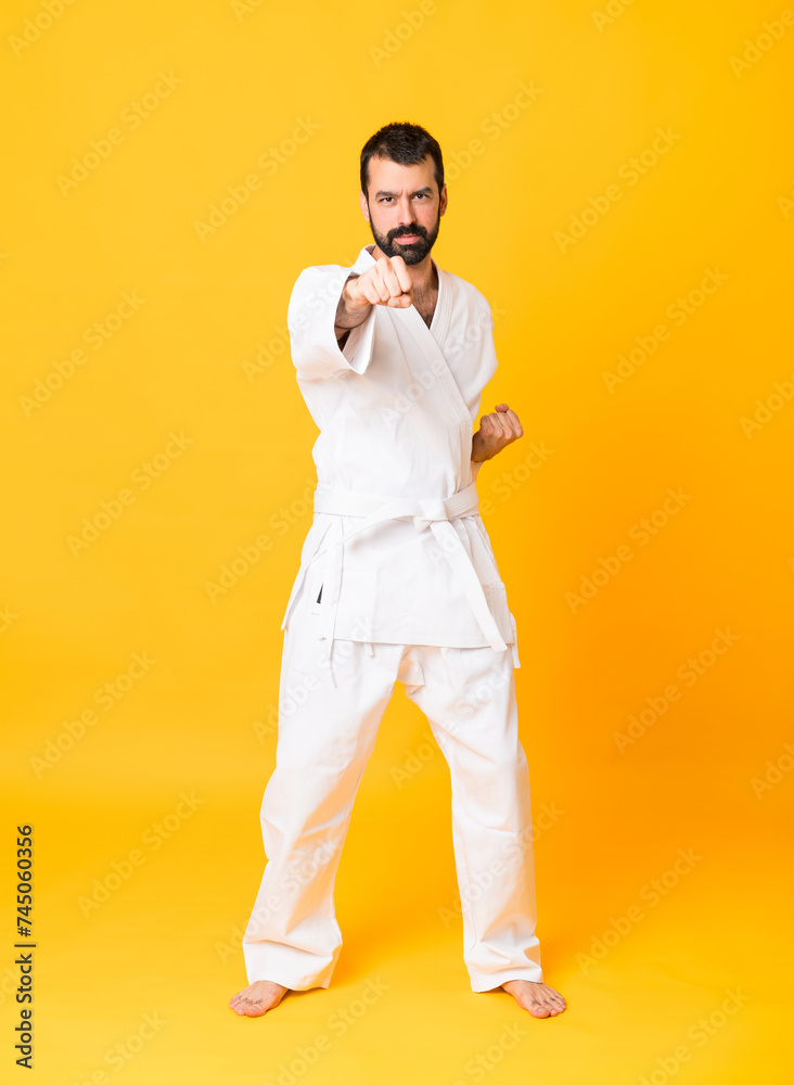 Full-length shot of man over isolated yellow background doing karate Full-length shot of man over isolated yellow background doing karate