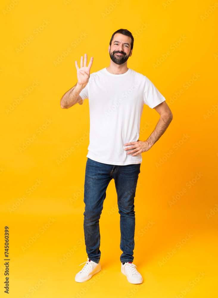 Full-length shot of man with beard over isolated yellow background happy and counting four with fingers Full-length shot of man with beard over isolated yellow background happy and counting four with fingers