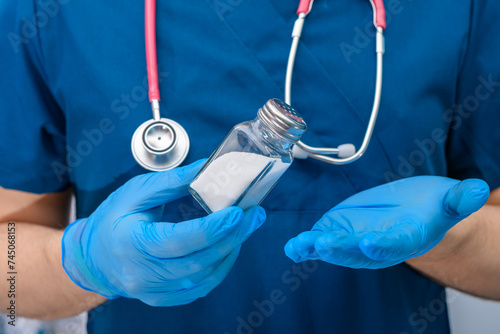 Solniczka z białą solą kuchenną trzymana w rękach przed doktora
