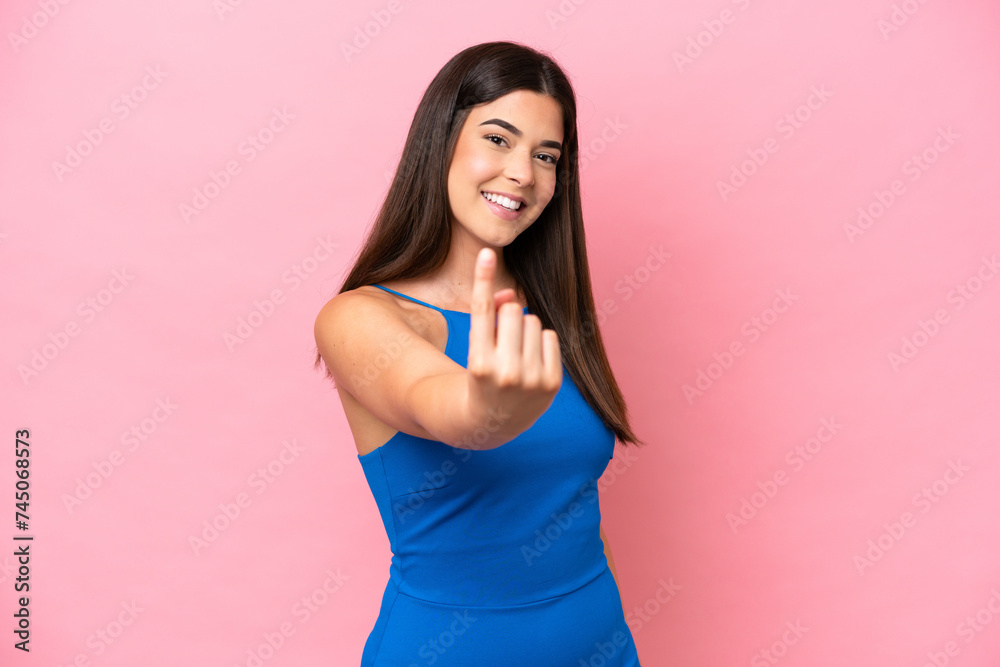 Young Brazilian woman isolated on pink background doing coming gesture Young Brazilian woman isolated on pink background doing coming gesture