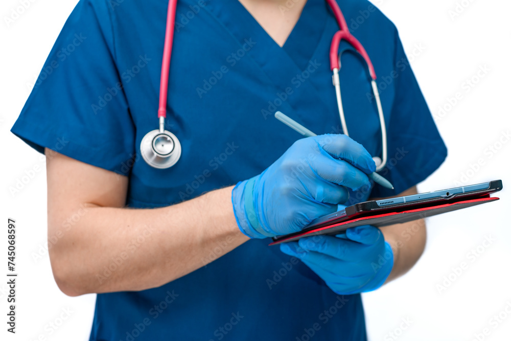 Lekarz ubrany w niebieski kitel medyczny pisze na tablecie, wystawia skierowania na badania i recepty - obrazy, fototapety, plakaty 