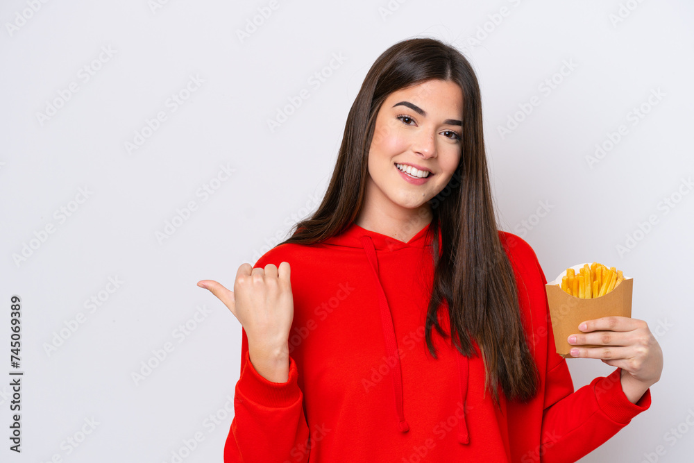 Young Brazilian woman catching french fries isolated on white background pointing to the side to present a product Young Brazilian woman catching french fries isolated on white background pointing to the side to present a product