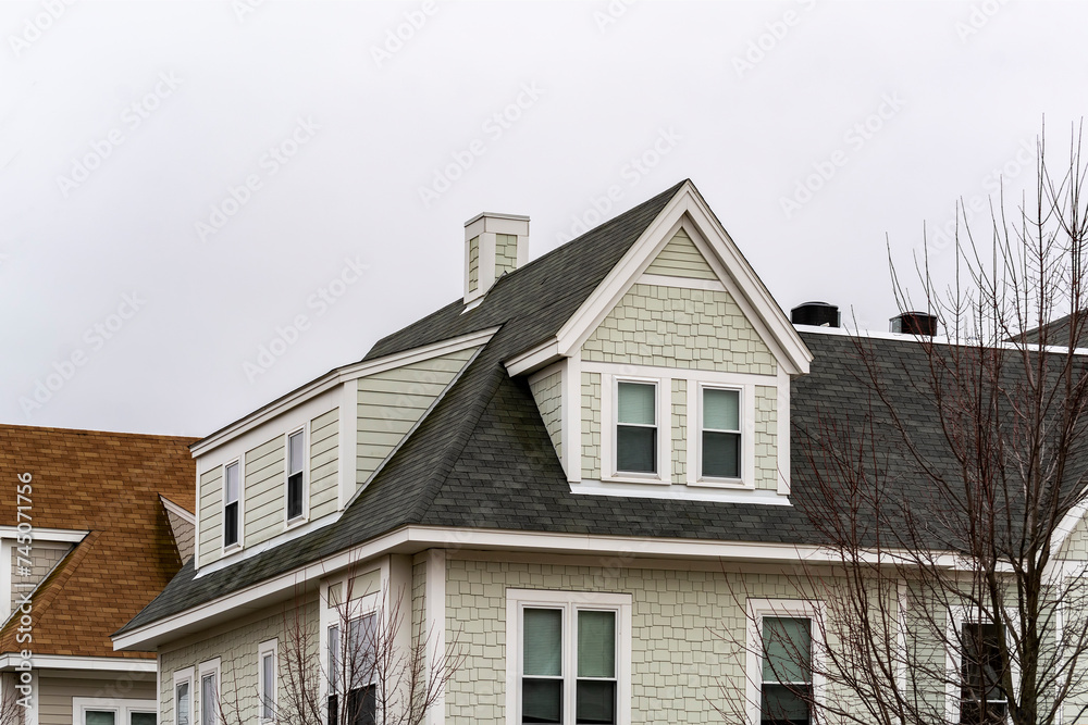 Dormer windows and sloped shingle roof of a newly built single-family home on a winter day, Boston, MA, USA