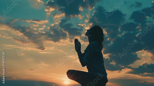 Silhouette of woman kneeling down praying for worship God at sky background. Christians pray to jesus christ for calmness. In morning people got to a quiet place and prayed. copy space photo