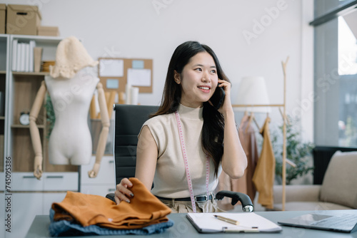 Female fashion designers use smart phones and use laptops with digital tablet computers to get orders from customers.