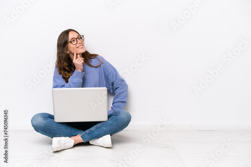 Carta da parati Young caucasian woman with a laptop sitting on the floor isolated on white backg