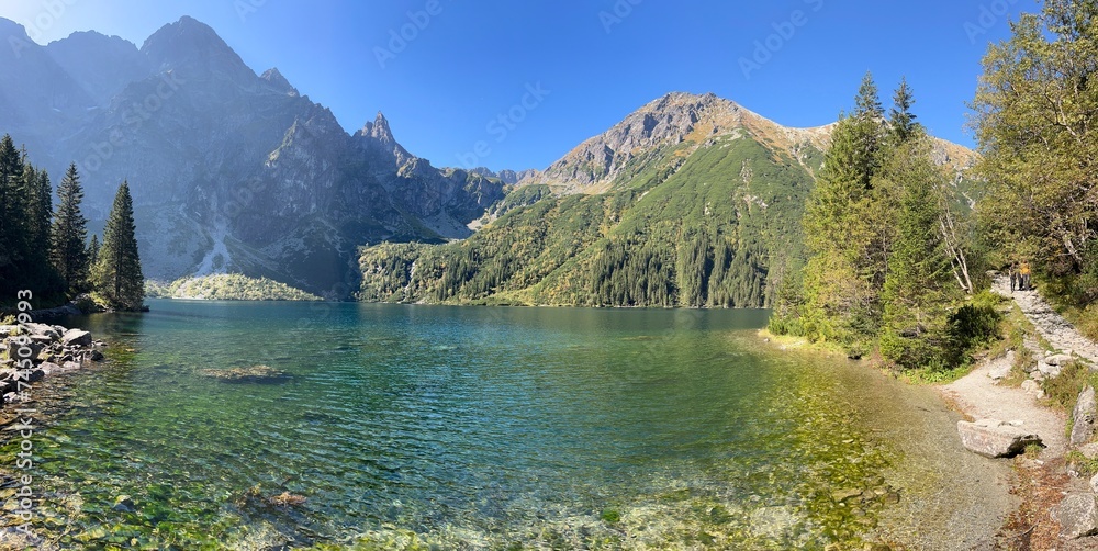 Pristine turquoise water of Morskie Oko Lake in Poland's Tatra National Park, surrounded by forest and mountain peaks, including Mieguszowiecki Szczyt Wielki, Mnich and Miedziane - obrazy, fototapety, plakaty 
