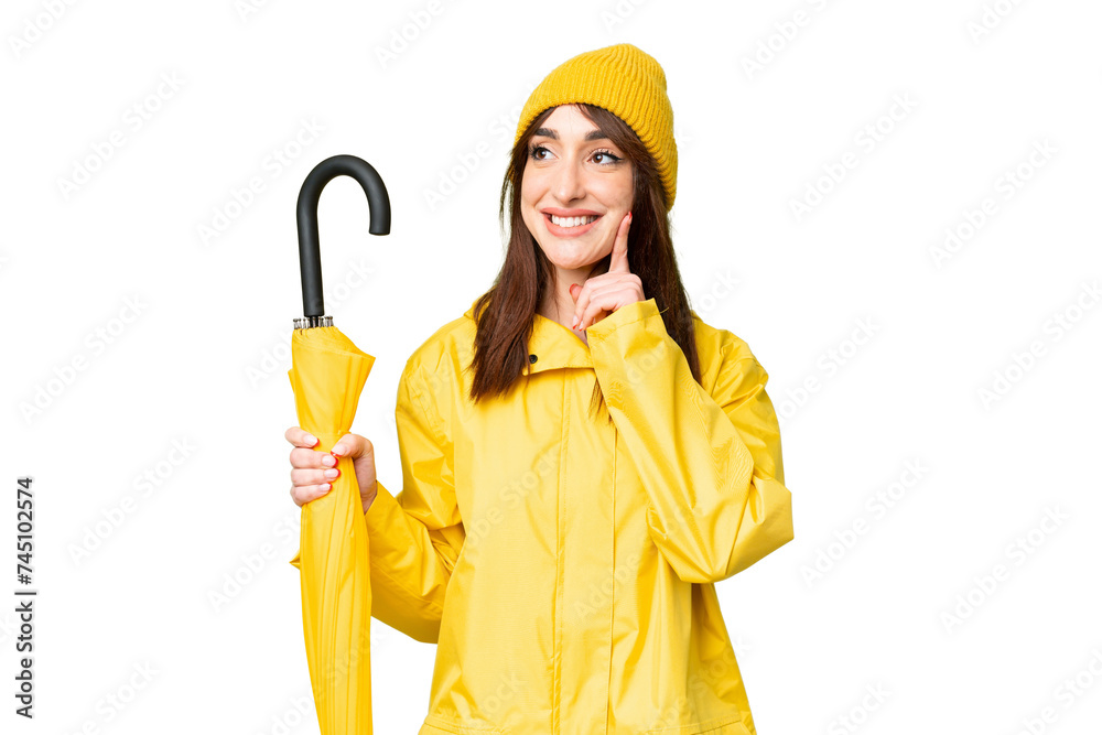 Young caucasian woman with rainproof coat and umbrella over isolated chroma key background thinking an idea while looking up Young caucasian woman with rainproof coat and umbrella over isolated chroma key background thinking an idea while looking up