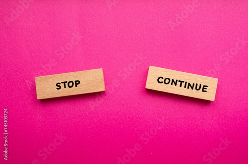 Stop or continue words written on wooden blocks with pink background. Conceptual symbol. Copy space. photo