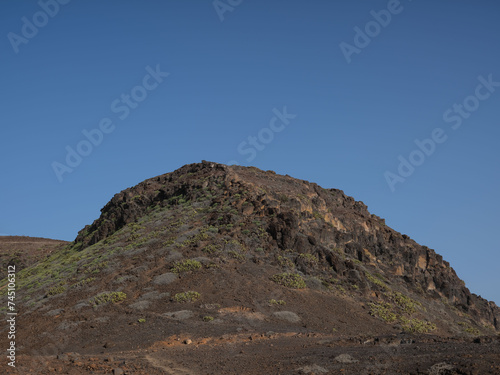 Hill and vegetation in desert landscape and blue sky on the edge of Las Palmas in the Canary islands, Spain