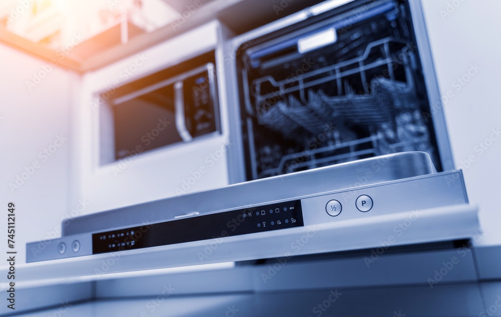 The white kitchen and opened dishwasher with clean dishes The white kitchen and opened dishwasher with clean dishes