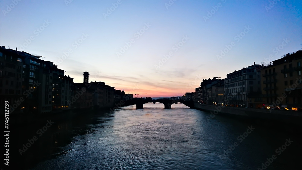 Firenze, Italy - 04.07.2018: Sunset view of River Arno from Ponte Vecchio with a cloudy sky
