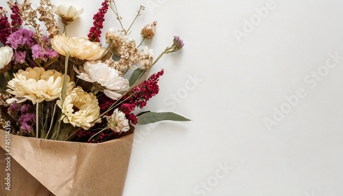 Dry flowers in bunches in brown craft paper packaging on white background. Flat lay photo