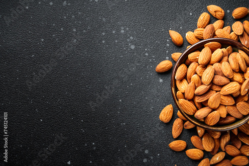 Almond nuts in bowl at black background.
