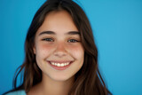 Cute Hispanic teen girl: Bright-eyed girl with a beaming smile and freckles, set against a cheerful blue background.