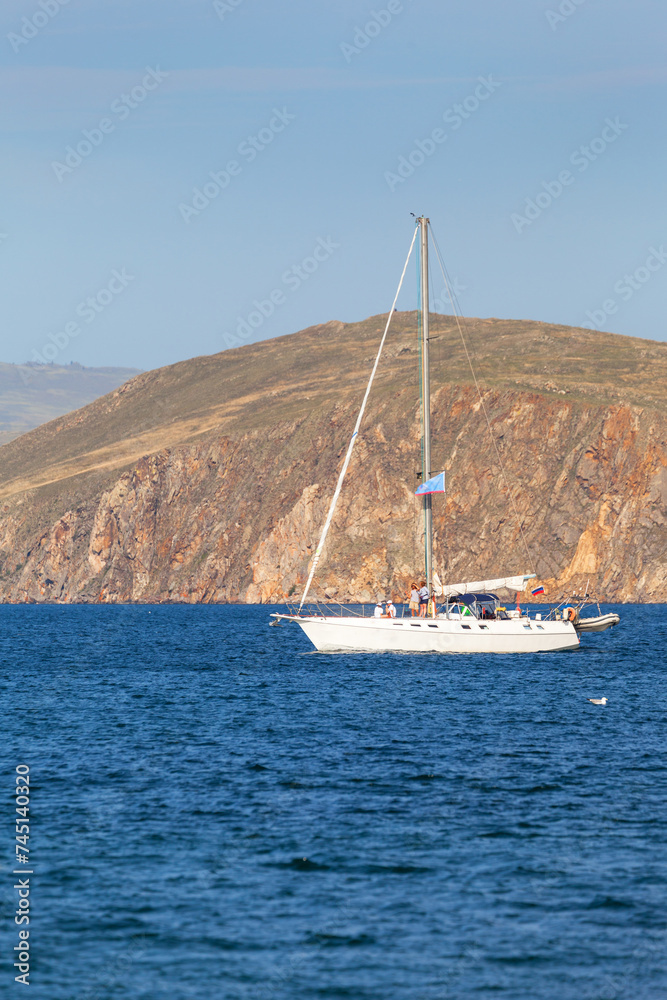 Summer holiday on Baikal Lake. Tourists relax with their family on a pleasure sailing yacht and travel along the rocky shore of Olkhon Island