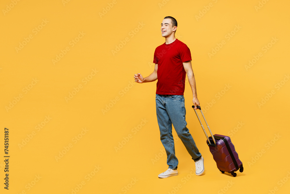 Traveler happy man wears red t-shirt casual clothes hold bag walk go isolated on plain yellow orange background. Tourist travel abroad in free spare time rest getaway. Air flight trip journey concept. Traveler happy man wears red t-shirt casual clothes hold bag walk go isolated on plain yellow orange background. Tourist travel abroad in free spare time rest getaway. Air flight trip journey concept.