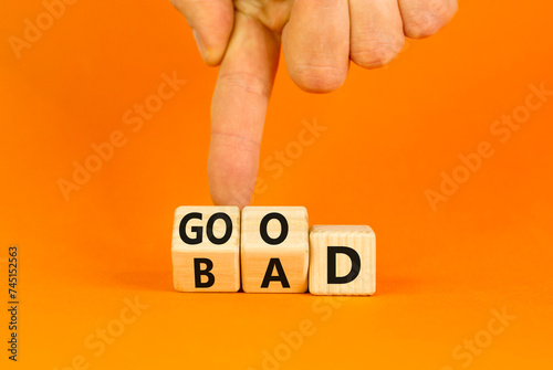 Good or bad symbol. Turned wooden cubes and changed the word bad to good. Beautiful orange table, orange background, copy space. Businessman hand. Business and bad or good concept.