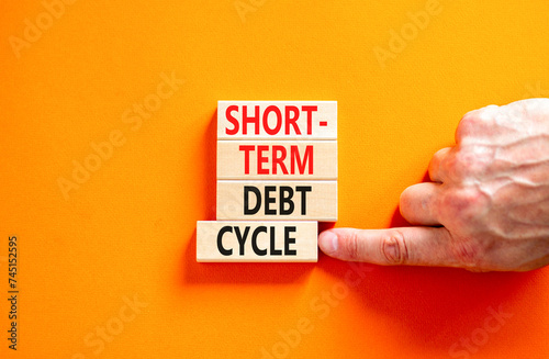 Short-term debt cycle symbol. Concept words Short-term debt cycle on beautiful wooden block. Beautiful orange table background. Businessman hand. Business Short-term debt cycle concept. Copy space.