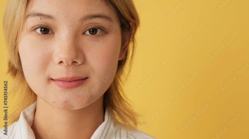 Fototapeta premium Portrait of young woman looking at camera, isolated on yellow background in studio